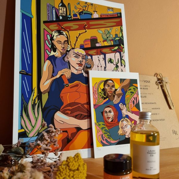 Print of two females, one cutting the others hair in the kitchen, on a wall in a massage studio.